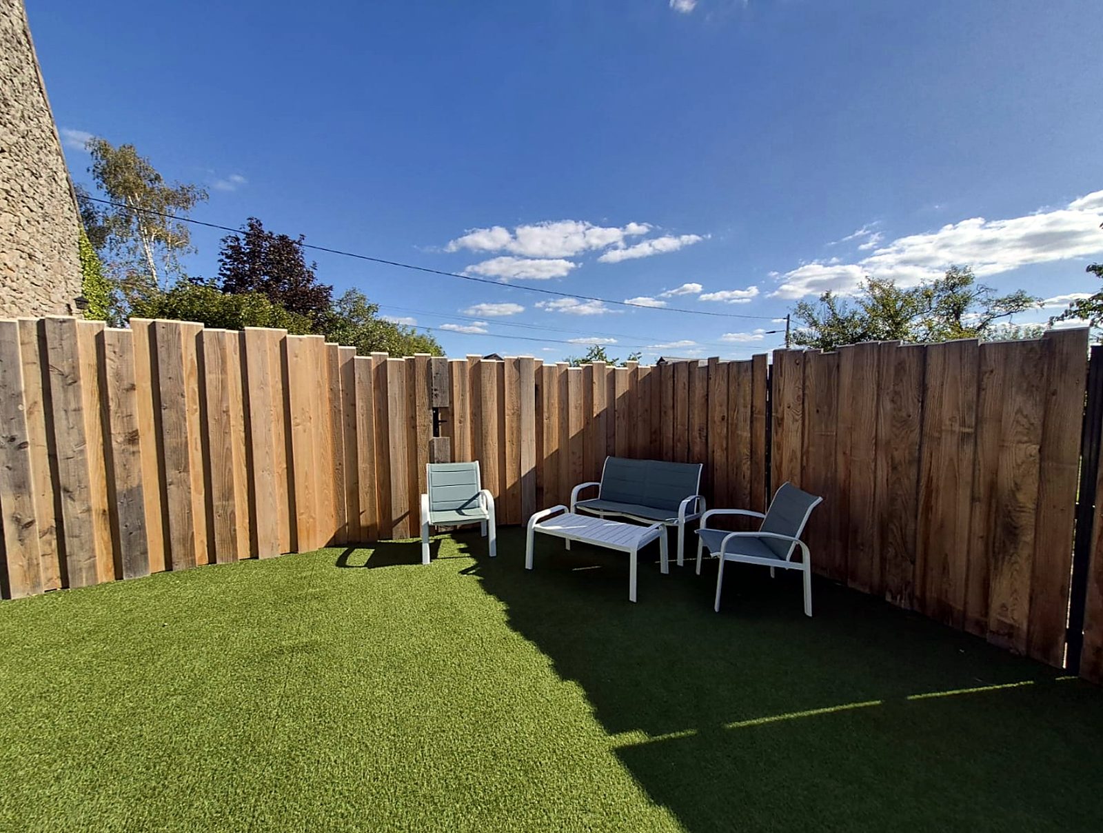 Clôture en bois bordant une terrasse en gazon synthétique