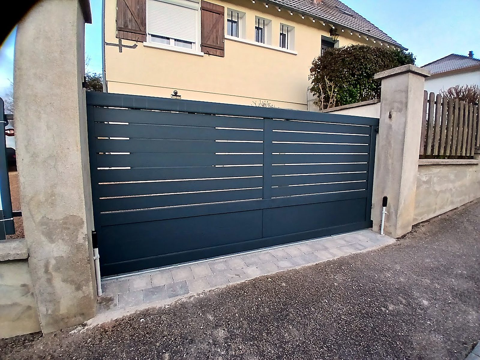 Entrée de portail en pavés entre deux piliers